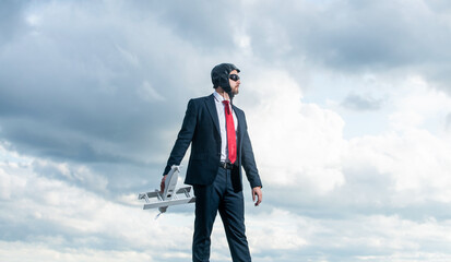 businessman in suit and pilot hat launch plane toy on sky background. promotion