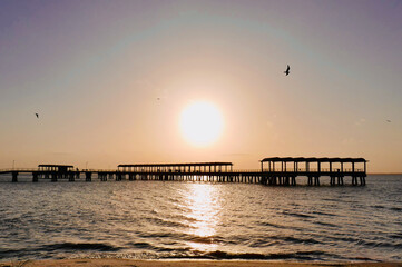 The sun setting over Jekyll Island Fishing Pier, with birds flying in the sky