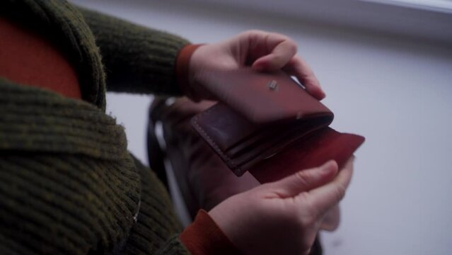 Distressed woman finds empty wallet, despair over finances evident. Delving into purse, hope fades as cash shortage hits, job search urgency grows amidst poverty.