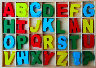 Wooden box of colorful wood english letters. front view.  Letters and signs for DIY.  letters in...