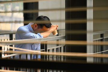 Shot of a male corporate worker feeling bad, worried standing at corridor of an office building - 797547352