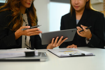 Cropped photo of young business people working together on a digital tablet at office desk