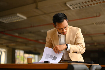 Serious busy professional business man checking document at an office building - 797550785