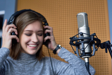 Cheerful female radio dj putting headphones on head while preparing for broadcasting