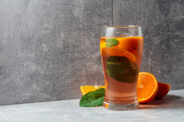 Summer cocktail with mint, and orange on a grey background.