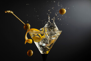 Classic dry martini cocktail with green olives and lemon peel on a black background.