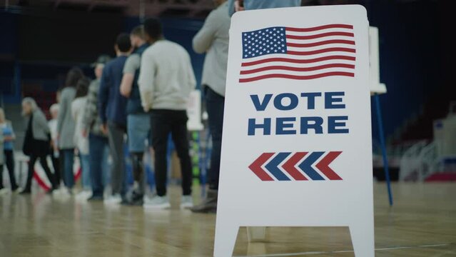 Vote here sign on the floor. Queue of multi ethnic American citizens come to vote in polling station. National Election Day in United States. Political races of US presidential candidates. Civic duty.