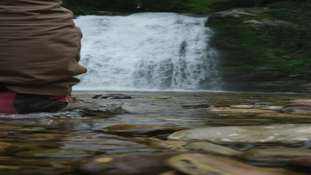 Traveler Tourist standing in forest watching beautiful waterfall. Environment, water supply, tourism concept. Water Flowing on Rocks Slow Motion. Tropical Vacation. Footage Shot in 4K. 16:9 ratio.