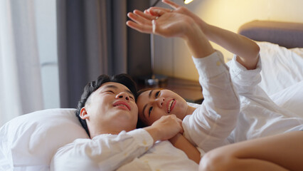 Top view young couple asia people lying down talk on bed relax smile hold hands look at ring on finger. Sweet happy lover asian man woman fall in true love new family life begin just married moment.