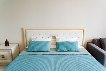 A rectangular wood bed with azure bedding in a bedroom next to a couch