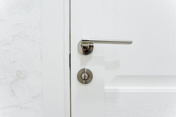 Silver door handle, furniture hardware, door locking mechanism, closed door to the room.