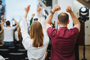 A group of people are joyfully gesturing with raised hands at a leisure event