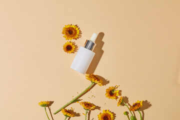 Empty label serum bottle decorated against the background in beige color with fresh Calendula...