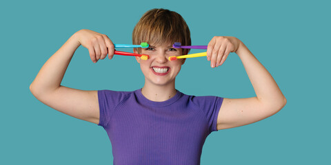 A smiling woman with healthy teeth holds a set of bright toothbrushes in her hands. The panorama. Oral hygiene. A place for your text.