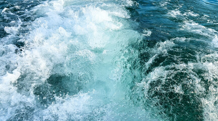 Sea water with foamy surface close-up. Boat trip on Lake Garda. Top view of turquoise rushing...