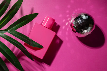 Rose perfume with palm leaf and disco ball on pink background, glamorous spray, elegant bottle,...
