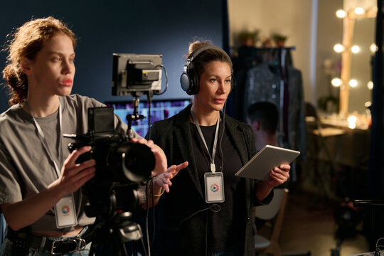 Waist up portrait of female director giving instructions to cast and crew on set during video production copy space