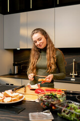 young girl in love in a green dress in the kitchen buttering bread preparing dinner