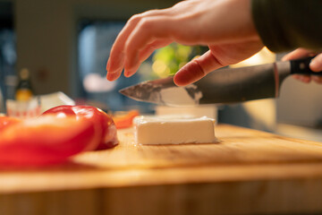 close-up of young girls hands slicing feta cheese for salad preparing dinner