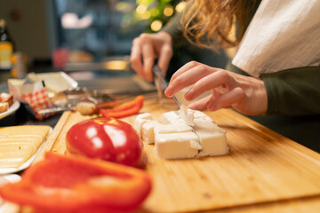 close-up of young girls hands slicing feta cheese for salad preparing dinner