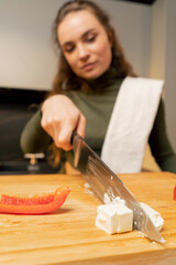 close-up in the kitchen a young girl cutting feta cheese on salad board preparing dinner