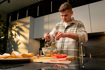 guy in love in the kitchen stirring Greek salad preparing romantic dinner
