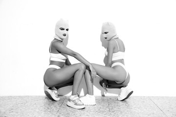 Two beautiful sexy women in underwear. Models wearing bandit balaclava mask. Hot seductive female...