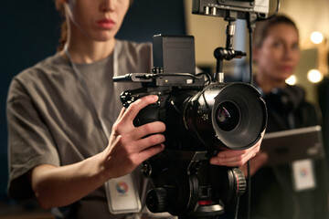 Close up of female hands holding professional video camera and operating equipment on set copy space