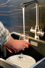 close-up of young guy in love in the kitchen washing the dishes after dinner