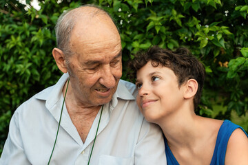 Grandfather and grandson enjoying a shared laugh in a serene garden - Elderly man and a young boy...