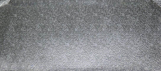 Background metal texture of a rough metal sheet with a shiny metallic surface reflecting light and...