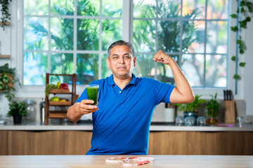 Asian Indian man in 40s having fresh freen juice in a glass
