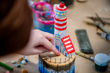 cute teen girl at a master class making a DIY wooden lighthouse made of wood, exhibition of crafts,...