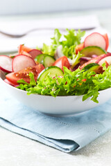 Healthy Salad with Tomatoes, Radish and Lettuce. Easy summer snack. Bright wooden background. Copy space.	