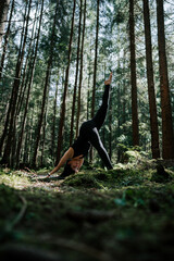 A young woman does yoga and meditates in the forest. Yoga and meditation concept. Yoga asanas. 