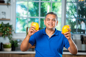 Indian asian man holding or presenting ripe mango fruit
