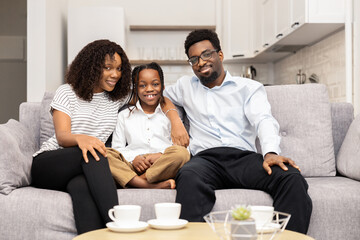 Happy Family Sitting Together On Couch With Smiles, Cozy Home Interior, Loving Relationship, Bond