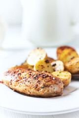 Grilled Chicken Breast with oven baked potatoes. Bright background. Close up.