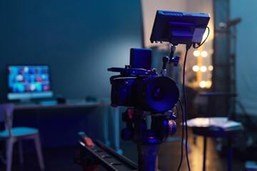Close up of professional digital camera on stand in video production studio with blue neon light...