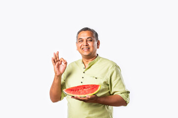 Indian asian man eating watermelon slice or tarbuj at home
