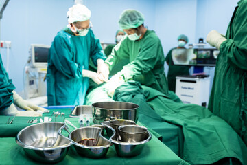 Disinfectant cup set for prepare breast surgery.Plastic surgeon sewing up breast of female patient...
