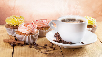 cup of coffee and cupcakes on the wooden background