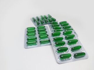 Vitamin E softgel Green capsules in blister pack on white background