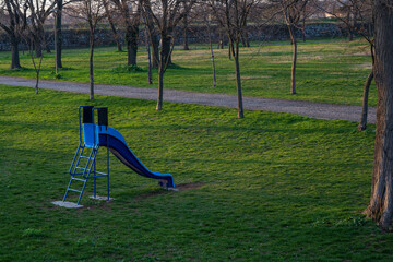 Blue plastic children's slide. A slide for children set in the forest in a beautiful green environment.
