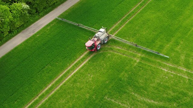 Drone flying over a tractor fertilizing a green field 4K