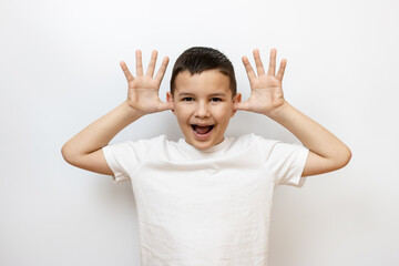 The guy raised his hands to his ears, shows a funny face. Sincere children's emotions. - obrazy, fototapety, plakaty