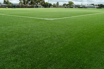 Clean and new artificial synthetic turf covers the surface of a public outdoor sports field. Vacant...