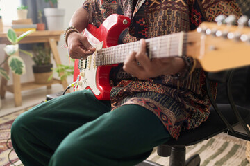Close-up of young talented male musician with electric guitar composing new music and recording it...