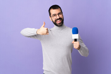 Adult reporter man with beard holding a microphone over isolated purple background giving a thumbs...