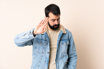 Caucasian man with beard over isolated background making stop gesture and disappointed